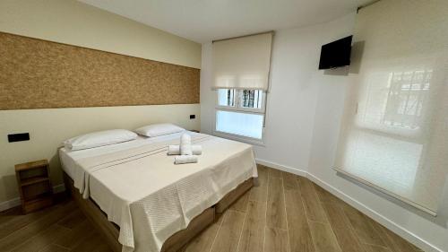 a bedroom with a bed with white sheets and a television at Casa Martina in Zaragoza