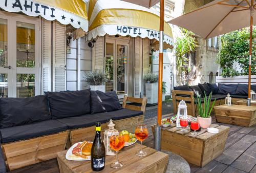 a patio with a couch and two tables with wine glasses at Hotel Tahiti in Viareggio