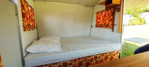 un petit lit sur le côté d'une remorque dans l'établissement Caravane vintage, à Camoël