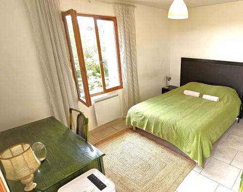 une chambre avec un lit vert et une fenêtre dans l'établissement Maison provençale au milieu des champs, à Robion
