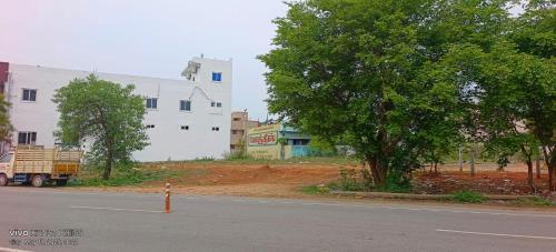 an empty street with a white building and a tree at SSN Residency in Tiruvannāmalai