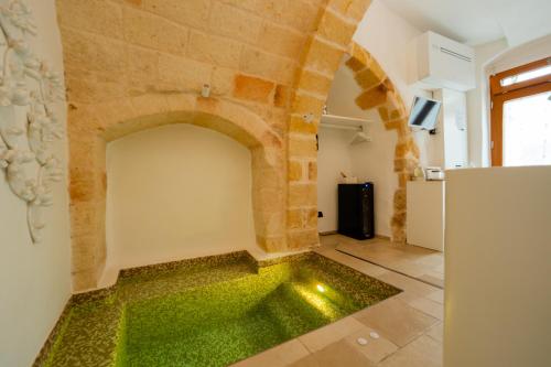 a room with a stone wall and green flooring at Il Fico Luxury Suite & SPA in Polignano a Mare