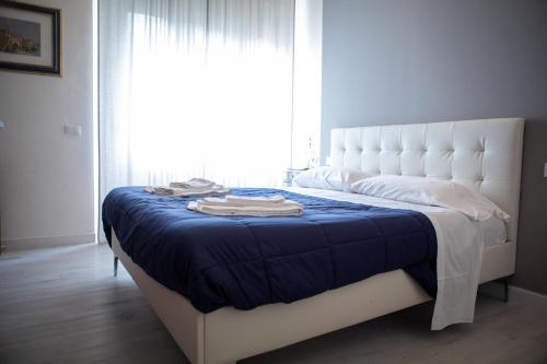 a white bed with a blue blanket and a window at Villa Giove Rooms in Prato