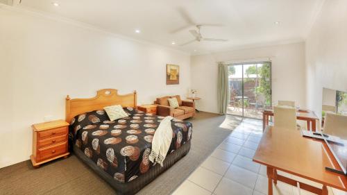 a bedroom with a bed and a desk and a couch at Emerald Gardens Motel & Apartments in Emerald