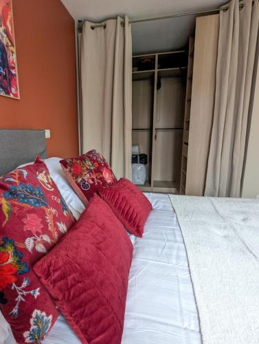 - un lit avec des oreillers rouges dans l'établissement Villa Evasion 10 pers Clim, à Saint-Martin-de-Londres