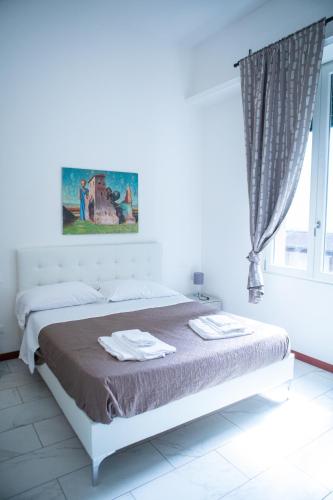 a white bedroom with a bed with towels on it at Villa Giove Rooms in Prato