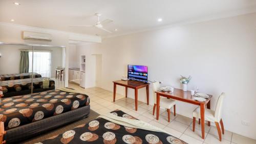 a living room with a bed and a desk with a television at Emerald Gardens Motel & Apartments in Emerald