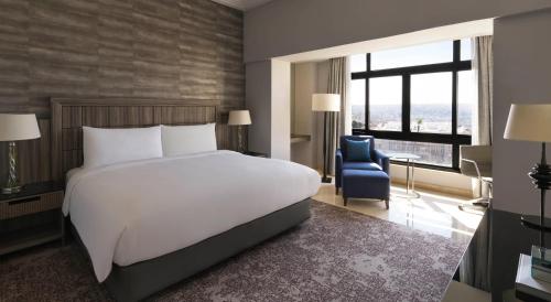 a bedroom with a large white bed and a blue chair at InterContinental Amman Jordan by IHG in Amman