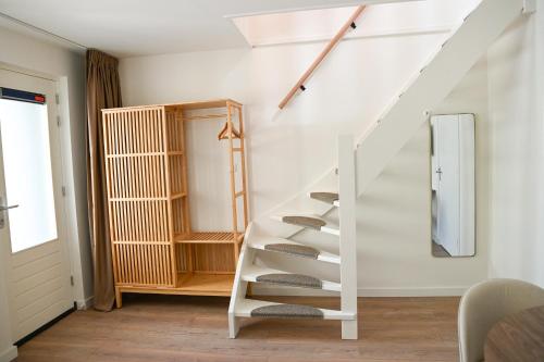 a white staircase in a room with a mirror at High Street Apartments in Zandvoort