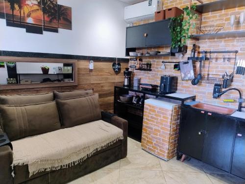 un soggiorno con un divano e un muro di mattoni di PraiAna Loft Arraial do Cabo ad Arraial do Cabo