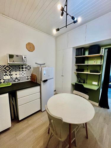 Il comprend une cuisine équipée d'une table blanche et d'un réfrigérateur blanc. dans l'établissement Appartement à 3 minutes de la gare, à Libourne