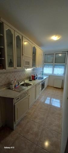 ヘーヴィーズにあるFavorite apartmentのタイルフロアのキッチン(白いキャビネット付)