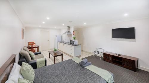 a bedroom with a bed and a living room with a tv at Emerald Gardens Motel & Apartments in Emerald