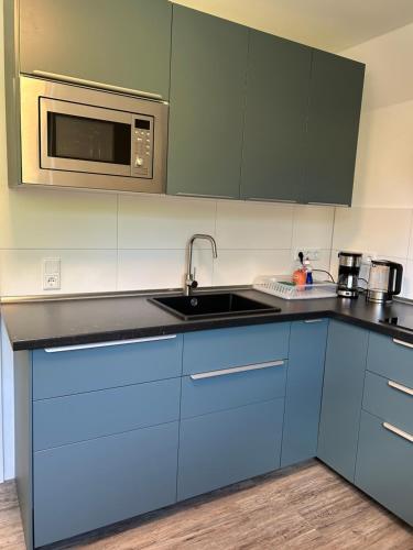 a kitchen with blue cabinets and a microwave at Ferienwohnung am Uniklinik Lübeck in Lübeck