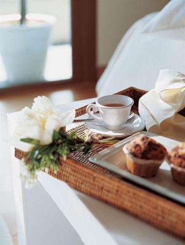 バトゥミにあるAparthotel Old Cityのベッドの上に置かれたコーヒーとマフィンの入ったトレイ