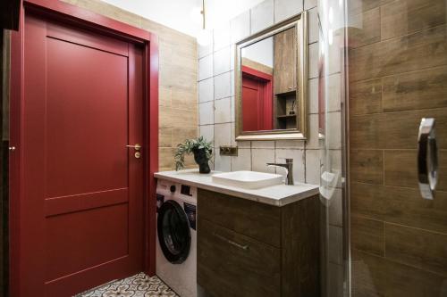 a bathroom with a sink and a red door at Polpo Apartments B&B in Łódź