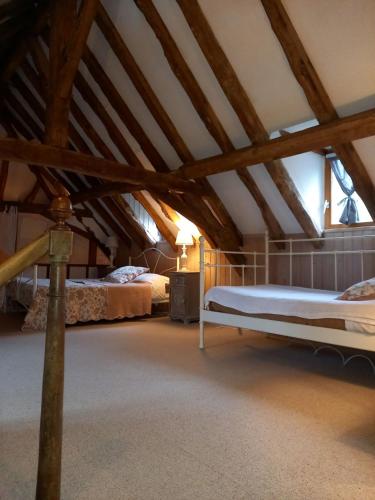 Cette chambre mansardée comprend 2 lits et des poutres apparentes. dans l'établissement Gite les taloches, à Tourtoirac