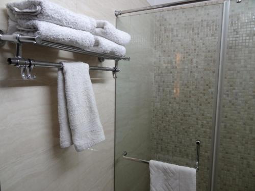 a bathroom with a shower with white towels at Venizia Sarovar Portico in New Delhi