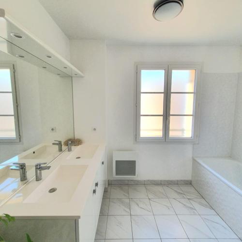 une salle de bain blanche avec un lavabo et un miroir dans l'établissement COSY HOME near DISNEYLAND PARIS, à Serris