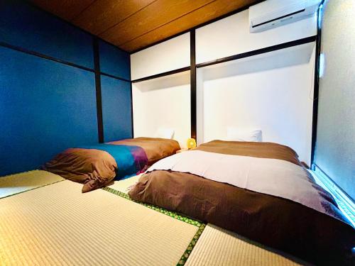 由布市にある岳見の宿 天然温泉 屋外水風呂付一棟貸しビラの青い壁の部屋にベッドが2つある