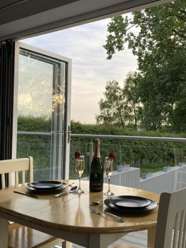 a table with a bottle of wine and two glasses at Orchard Cottage At Gretna in Gretna