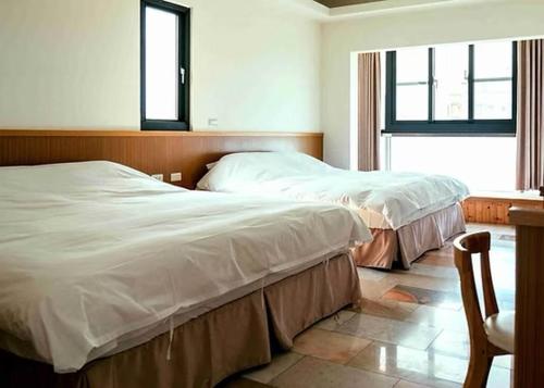 two beds in a bedroom with a window at Grand Uncle in Ta-p'ai-chu