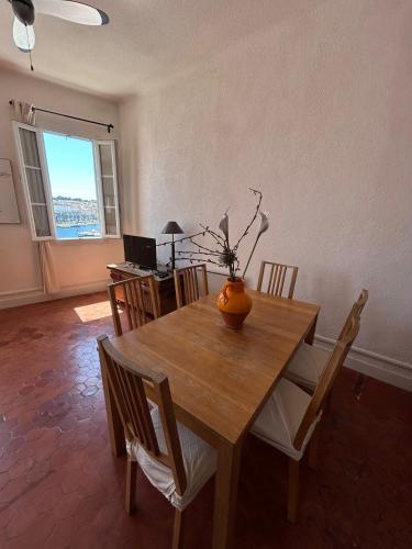 une table de salle à manger avec un vase de fleurs dessus dans l'établissement Spacious 2-bed apartment with direct Port view, free parking, à La Ciotat