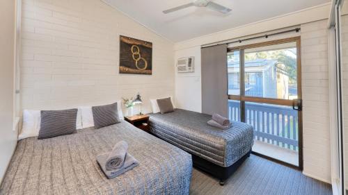 a bedroom with two beds and a balcony at Emerald Gardens Motel & Apartments in Emerald