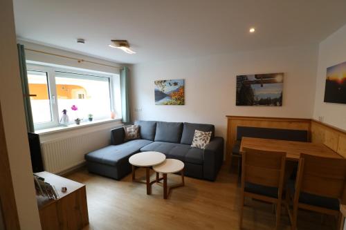 a living room with a blue couch and a table at Ferienwohnungen ARIKOGEL Bad Goisern in Bad Goisern