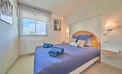 une chambre avec un grand lit avec des oreillers bleus dessus dans l'établissement L'Amourette - Appartement 4 personnes - Piscine Parking, à Saint-Tropez