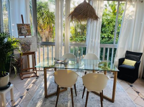 une table et des chaises en verre dans une pièce avec fenêtres dans l'établissement Superbe 2 pièces à Cannes, à Cannes