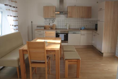 a kitchen with a wooden table and chairs and a kitchen with white cabinets at Appartements-Steinkirchner in Straubing