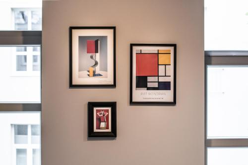 a group of framed pictures on a wall with windows at Polpo Apartments B&B in Łódź