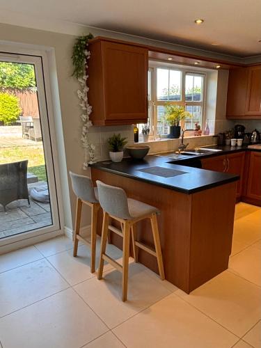 a kitchen with a island with stools in it at Spacious four bed detached home in Nottingham in Nottingham