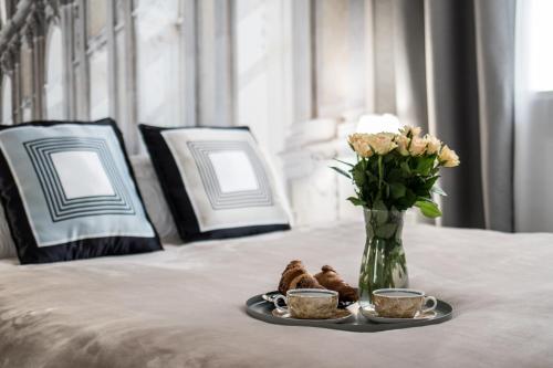 a vase with flowers and pastries and two cups on a bed at Polpo Apartments B&B in Łódź