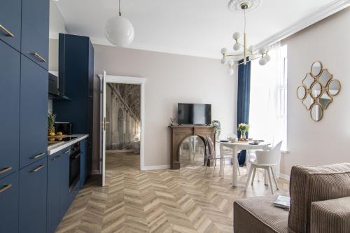 a kitchen and living room with blue cabinets and a table at Polpo Apartments B&B in Łódź
