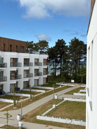 a large white building with trees in the background at APARTAMENT BALTICHOFF FUN with Sea View, Basen, Spa, Gym, Sauna, Hala sportowa z kortem tenisowym in Gąski