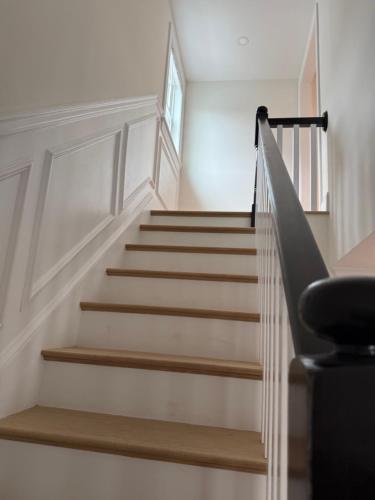 a staircase in a home with white walls and wooden steps at Forest Hill condos -Boston in Boston