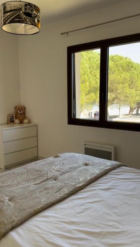 une chambre avec un lit blanc avec une fenêtre dans l'établissement Appartement les pieds dans l eau, à Carcans