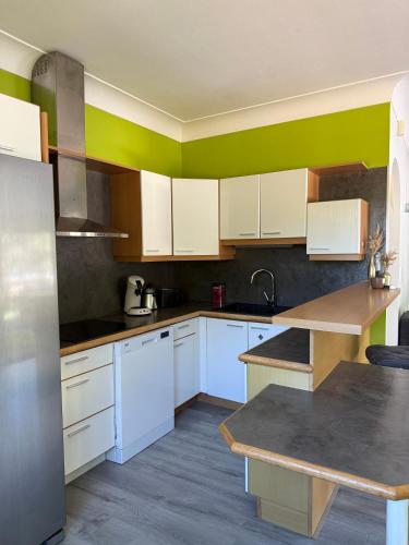 - une cuisine avec des placards blancs et un mur vert dans l'établissement Appartement les pieds dans l eau, à Carcans