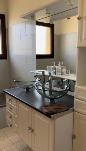 La salle de bains est pourvue d'un lavabo en verre et d'un miroir. dans l'établissement Appartement les pieds dans l eau, à Carcans