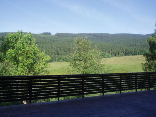 a fence with a view of a field and trees at Hotel Čertův Mlýn, Špičák, Železná Ruda, Šumava in Špičák