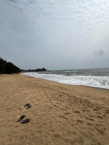 two pairs of flip flops on a beach with the ocean at Résidence Yavanie in Kribi