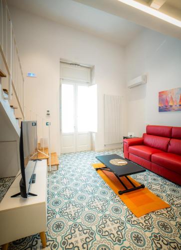 a living room with a red couch and a tv at Dimora Carafa apartment in Lecce