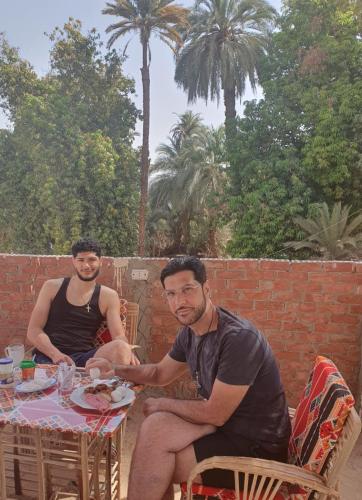 two men sitting at a table with a plate of food at Rayan Nubian Guest House in Aswan