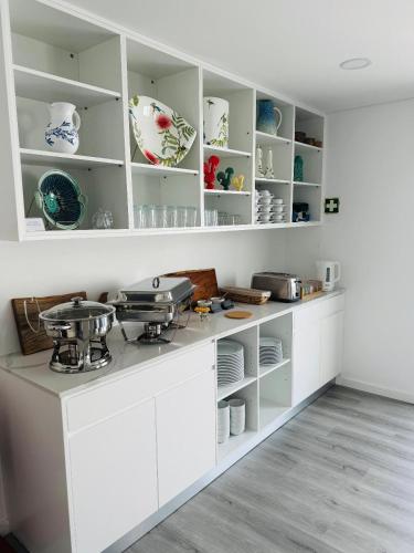 a kitchen with white cabinets and dishes on shelves at Bella Casa Bed and Breakfast in Ponta Delgada