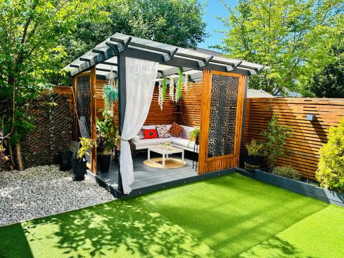 a garden with a pergola with a bench and grass at MeeZee Pearl Double Bed Lodge With Free Parking in Manchester