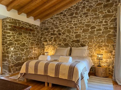 a bedroom with a bed in a stone wall at Quinta da Mata de Baixo in Dornes