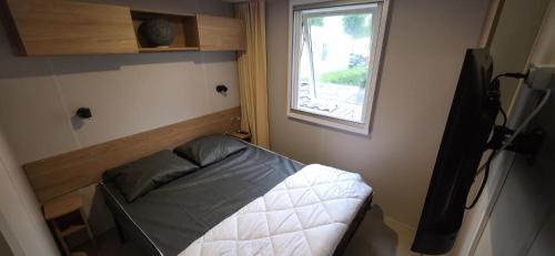 a small bed in a small room with a window at Mobilhome 6-8 pers - 3 ch - 1 sdb - Parc Aquatique in Vias