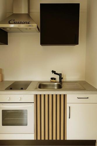 une cuisine avec un évier et une cuisinière four supérieur dans l'établissement T2 cosy, calme à 5 min de la Croisette, au Cannet